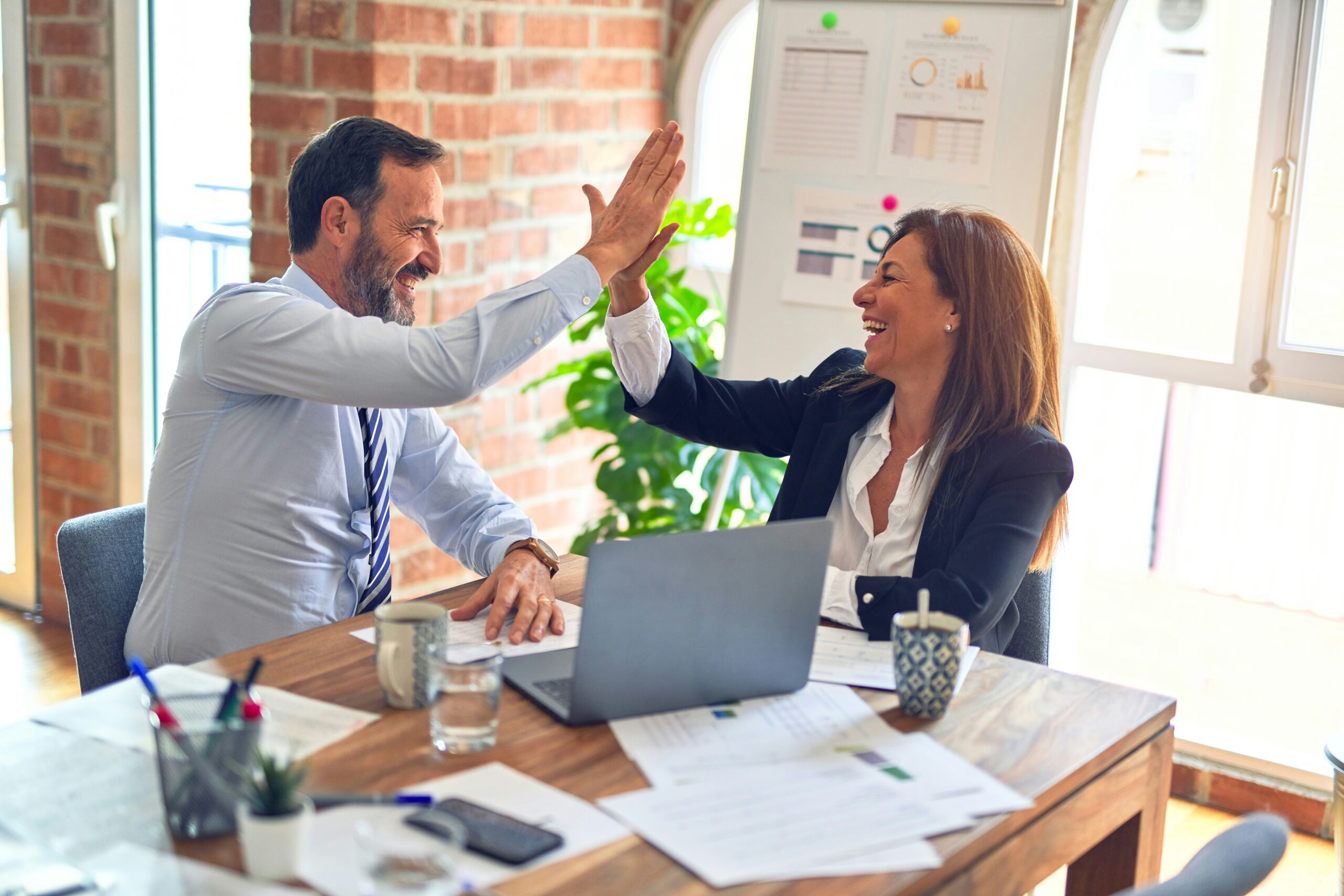 Employee Experience Photo Two coworkers celebrating a successful outcome with a high five in the office