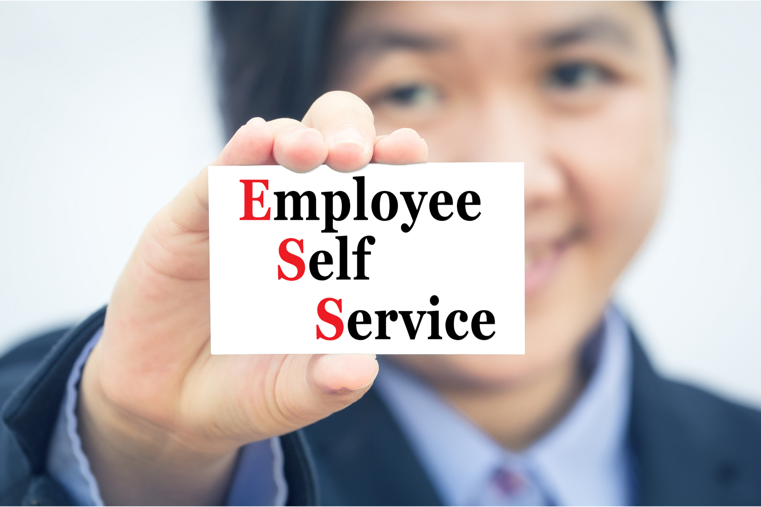 Person in a suit holding up a card that reads "Employee Self Service," with the letters E, S, S in red