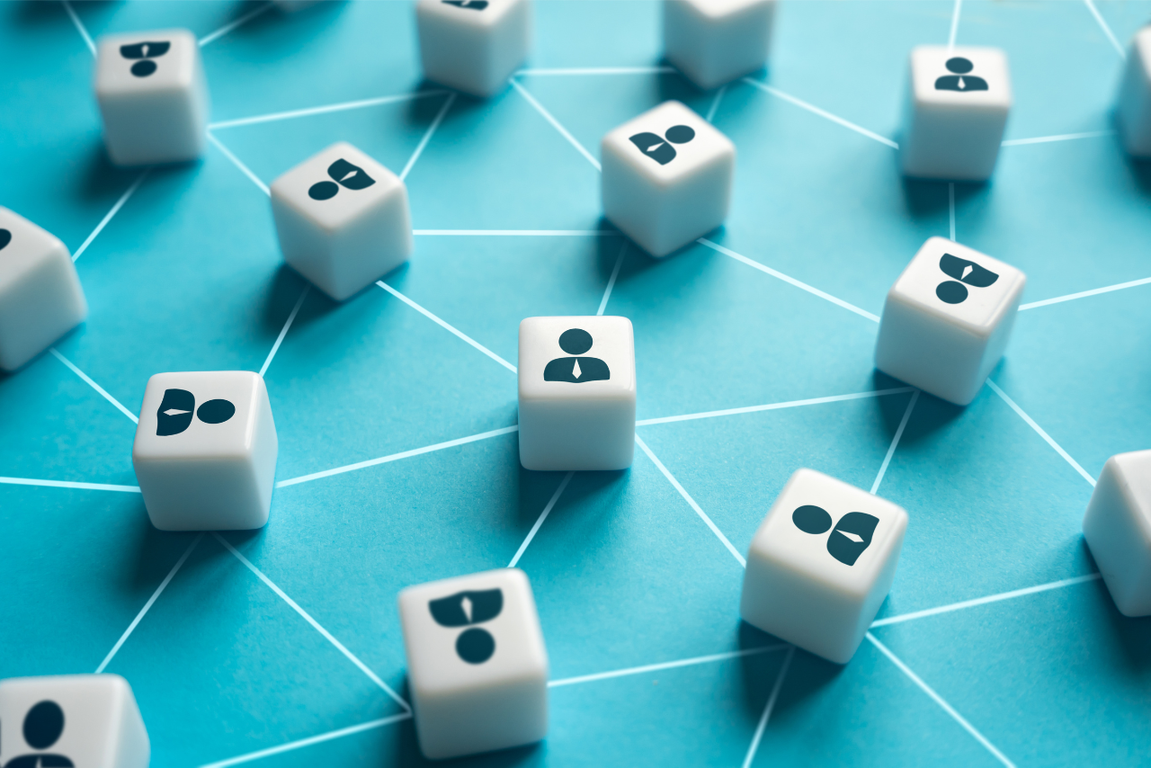 Connected Network of People Icons – Sincron HR White cubes with person icons spread across a blue surface, connected by a network of white lines